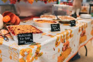 Westmount Realty Thanksgiving potluck dessert table with favorites like no-bake cherry cheesecake, cakes, pies, and cobblers.